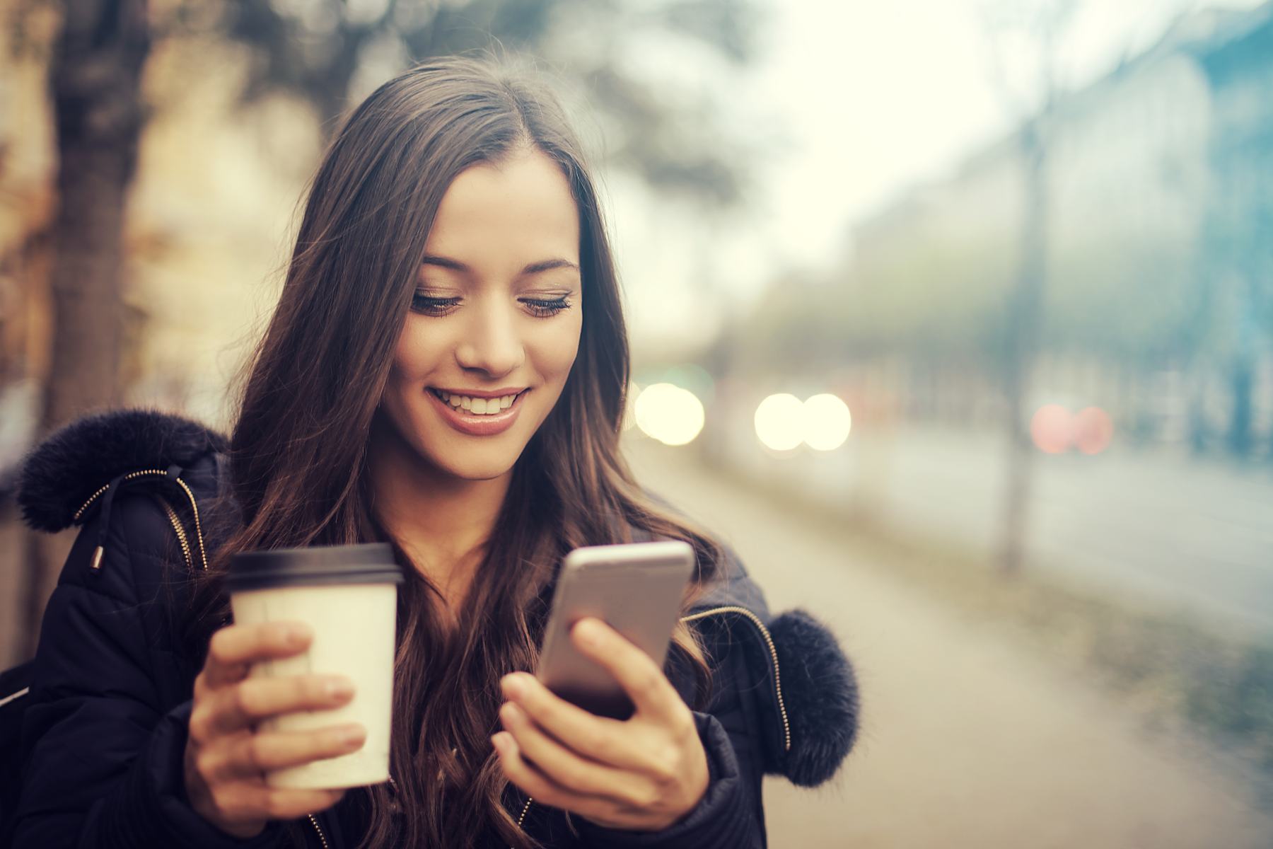 Woman holding coffee and phone